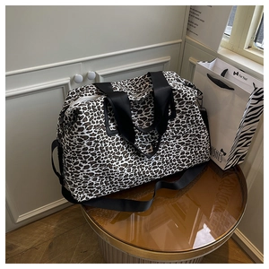 Dettaglio della borsa da viaggio leopardata con manici in nylon nero e fibbie in metallo