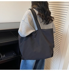 Vista detallada del bolso tote negro de gran capacidad al hombro con logo