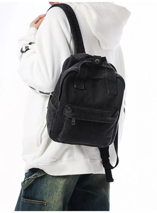 Detailansicht eines schwarzen Denim-Rucksacks mit Reißverschlusstasche an einem Model