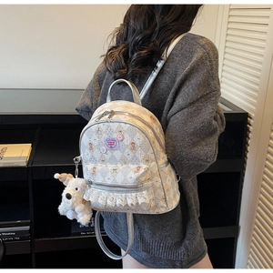 Vue détaillée du sac à dos matelassé argenté avec étiquettes roses et peluche de chien