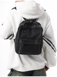 Detailansicht eines schwarzen Vintage-Rucksacks aus gewaschenem Denim an einem Model gezeigt