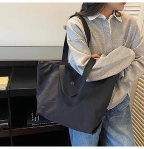 Detalle de un bolso tote grande de lona negra usado por una modelo en estilo casual