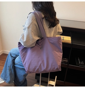 Vista detallada del bolso tote de lona morada con hebilla redonda y correa ancha