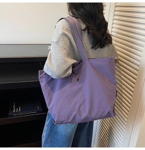 Vista detallada del bolso tote grande de nailon morado con correa ancha en una modelo