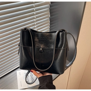 Gros plan sur un sac à bandoulière en cuir noir brillant avec logo embossé