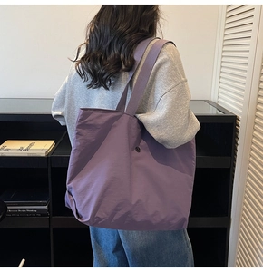 Detalle de un gran bolso tote morado al hombro en un ambiente interior minimalista