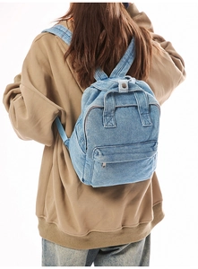 Rückansicht eines hellblauen gewaschenen Denim-Rucksacks auf einem Kapuzenpulli