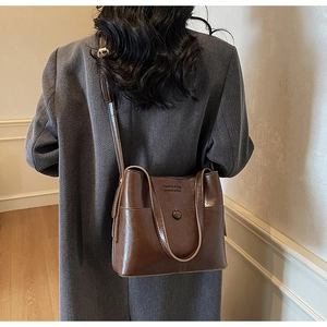 Détail d'un sac à bandoulière en cuir marron foncé vintage avec coutures et gravure mode