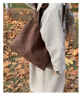 Detail of a dark brown vintage suede tote bag with a unique knot strap on the shoulder