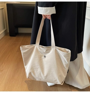 Detalle del bolso tote de tela beige de gran capacidad con cierre de presión metálico