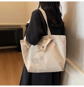 Detalle del bolso tote beige de gran capacidad en nailon con correas de hombro anchas y suaves