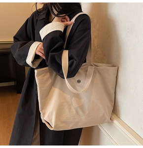 Detalle del bolso tote de nailon beige con hebilla magnética y correas dobles al hombro