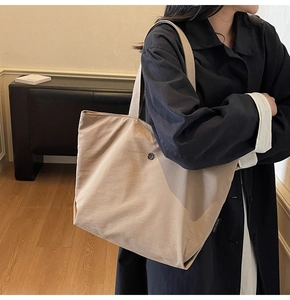 Detalle del bolso tote caqui claro con hebilla metálica redonda y etiqueta de marca