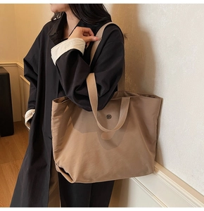 Detalle del bolso tote de nailon caqui con gran capacidad y logotipo metálico lateral