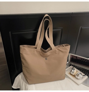 Detalle del bolso tote caqui de gran capacidad con broche de metal y correa ancha
