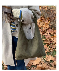Close-up of olive green suede Hobo bag with knot detail on the strap outdoors