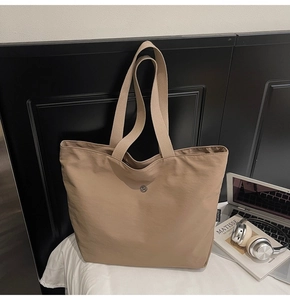 Primer plano de bolso tote de tela caqui con hebilla metálica y etiqueta de logo