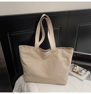 Detalle de un bolso tote minimalista de lona beige con asas suaves y amplio interior