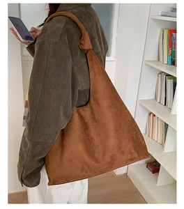 Detail of the brown suede tote bag featuring a unique knotted strap and spacious design