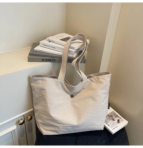 Detalle de bolso tote blanco crema en nailon texturizado con hebilla metálica decorativa