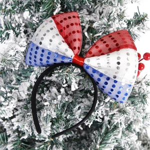 Detail of red white and blue sequined bow headband on snow covered pine branches