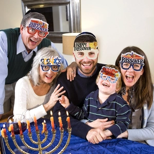 Family wearing colorful paper glasses with Happy Passover and Matzah motifs for photo props
