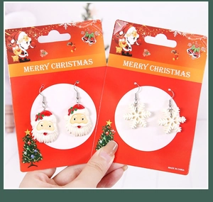 Détail des boucles d'oreilles Père Noël et flocon sur une carte de fête de Noël