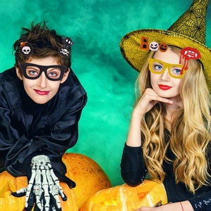 Kids wearing Halloween pumpkin glasses and witch hats for a spooky festive party celebration