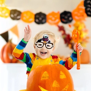 Kid wearing Halloween paper glasses with black cat and cauldron design at a festive party
