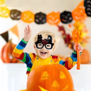Detail of paper Halloween glasses featuring pumpkins and terror time text on a smiling child
