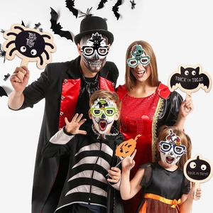 Family wearing Halloween paper glasses and props with pumpkins, ghosts and spider designs
