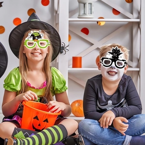 Kids wearing Halloween paper glasses with green witch and bat castle themed frames