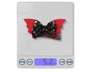 Detailed macro view showing the Halloween bat bow hair clip weighing 5.2g on a scale