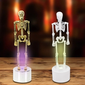 Halloween glowing skeleton ornaments with gold and white finishes on a wooden desk