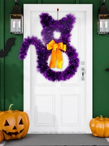 Detailed view of a purple sequined cat wreath with a yellow bow on a white door