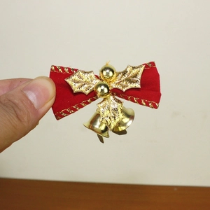Detail einer roten Samtschleife für Weihnachten mit Goldglöckchen und glitzernden Blättern