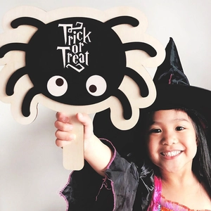 Halloween wooden trick or treat spider hand sign prop held by a girl for party fun