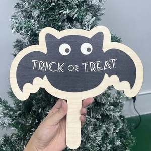 Detail showing a wooden bat-shaped Halloween sign with Trick or Treat text