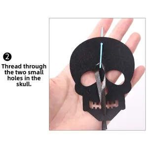 Detail of threading black ribbon through Halloween felt skull ornament using a blue needle