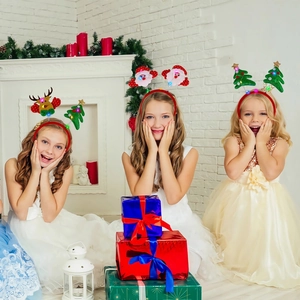 Tres niños con diademas navideñas luminosas LED, diseños de alce y árbol de Navidad