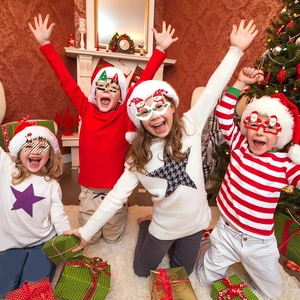 Group of happy children wearing assorted Christmas paper glasses at a festive holiday party