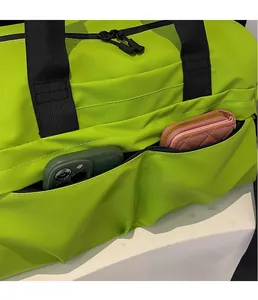 Detailansicht der neongrünen Reisetasche mit Seitentasche für Handy und Geldbörse