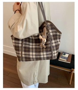 Gros plan d'un sac cabas à carreaux vintage avec lanières en cuir et lapin en peluche