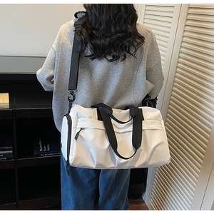Moderne weiße Reisetasche aus Canvas mit schwarzen Riemen, getragen in einem Interieur