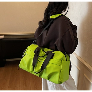 Detailansicht der fluoreszierenden grünen Reisetasche mit schwarzen Gurten am Modell
