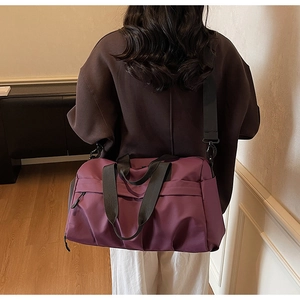 Dunkelviolette Reisetasche mit schwarzen Riemen an einem Modell zur Darstellung der Größe