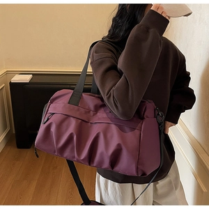 Detailansicht der weinroten Reisetasche mit großem Fassungsvermögen, getragen von einem Model