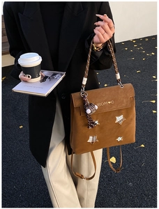Detail of brown frosted leather backpack with star patches and woven handle in outdoor setting