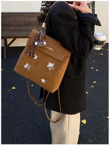 Detail of star patchwork and metal HOME logo on frosted caramel brown backpack