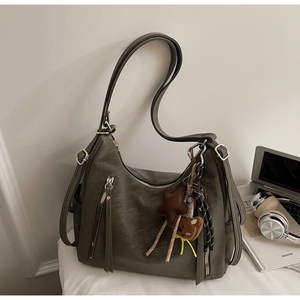 Détail du sac en cuir grainé vert olive avec double zip et charm ours tendance